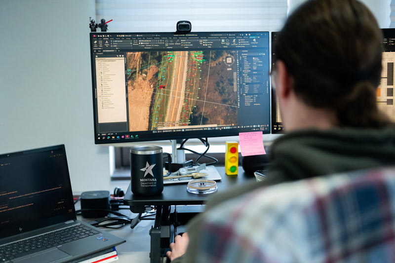 Person sitting at computer looking at a project drawing