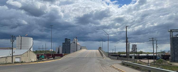 Looking south along the 7th Avenue North bridge in Havre, with the Burlington Northern Santa Fe Railway yard and industrial facilities visible on either side.
