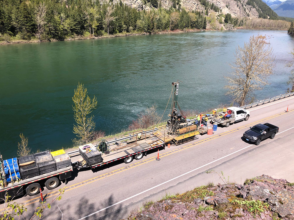 A truck drives through a construction area in Bad Rock Canyon. The Flathead River is in the background Image