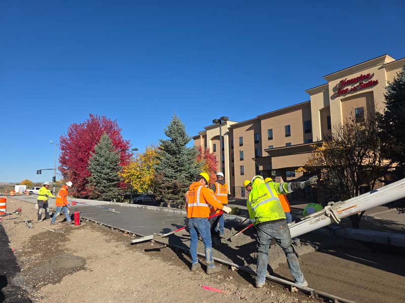 Looking northwest toward Gabel Road, crews pour concrete for the new sidewalk.