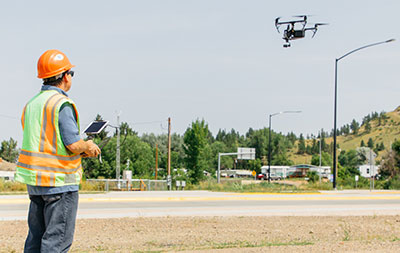 MDT personnel operating a drone by a road.