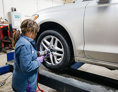 Image of a woman working on a vehicle.